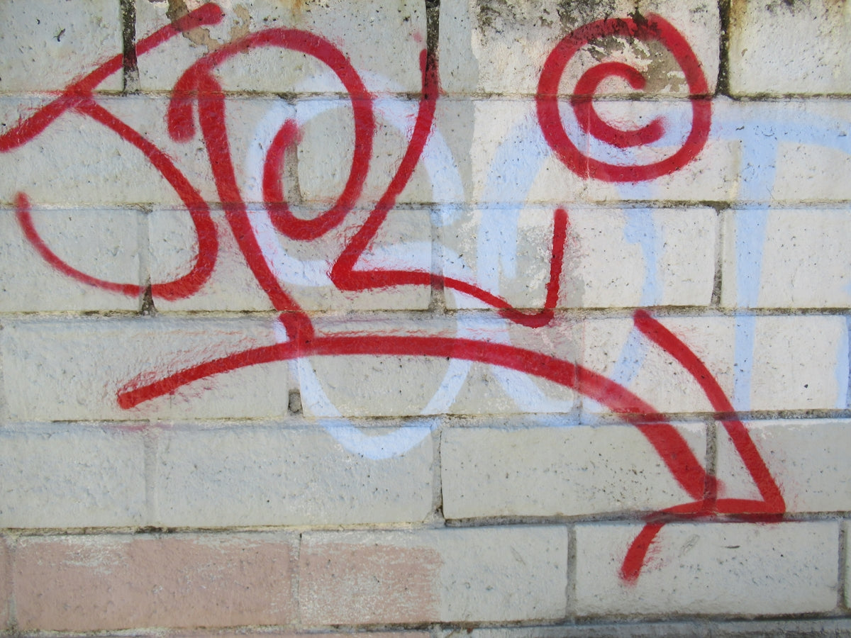 a red and white graffiti on a white wall