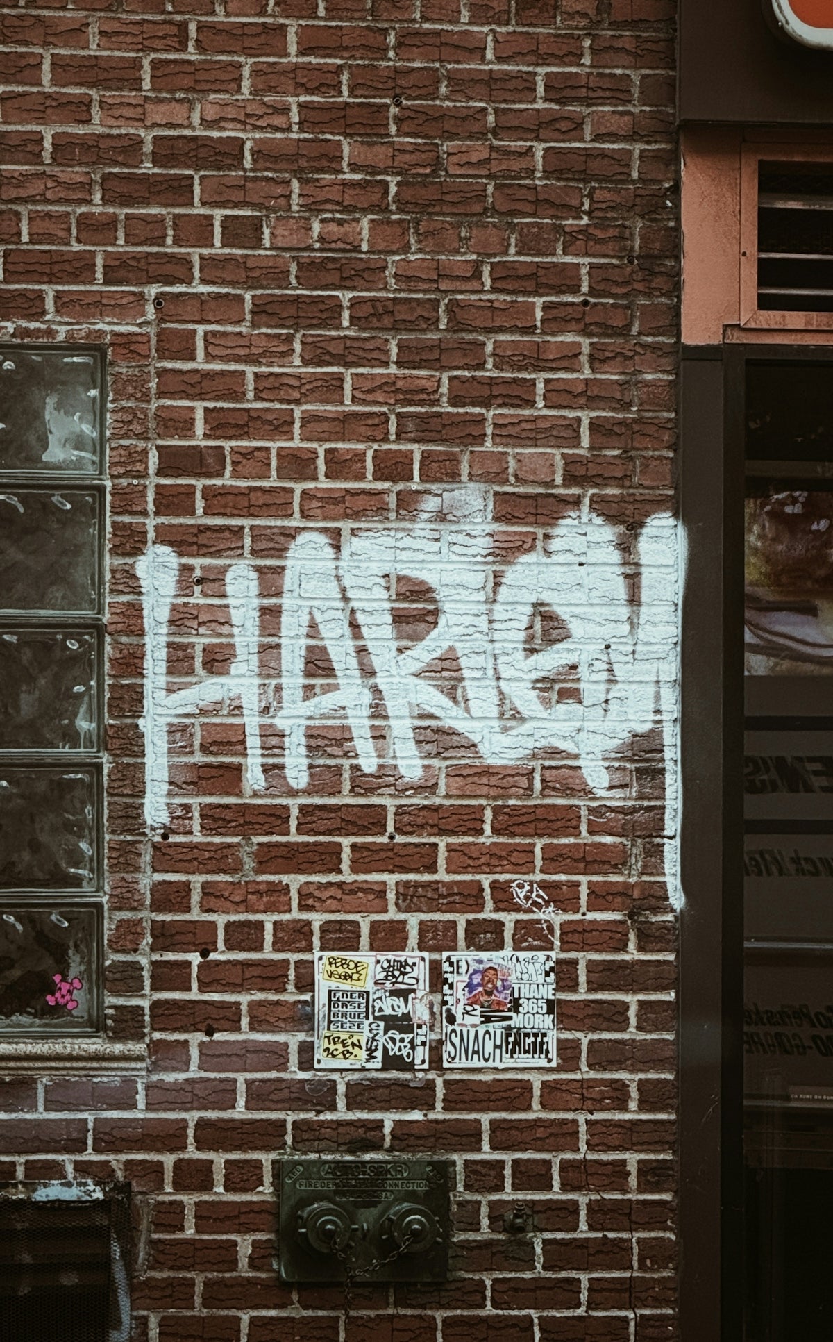 Graffiti on a brick wall says, harlem.