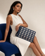 Denara studded denim clutch with seated female model on cobalt chair - creative view