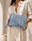 Woman holding the Marella studded light-wash denim clutch