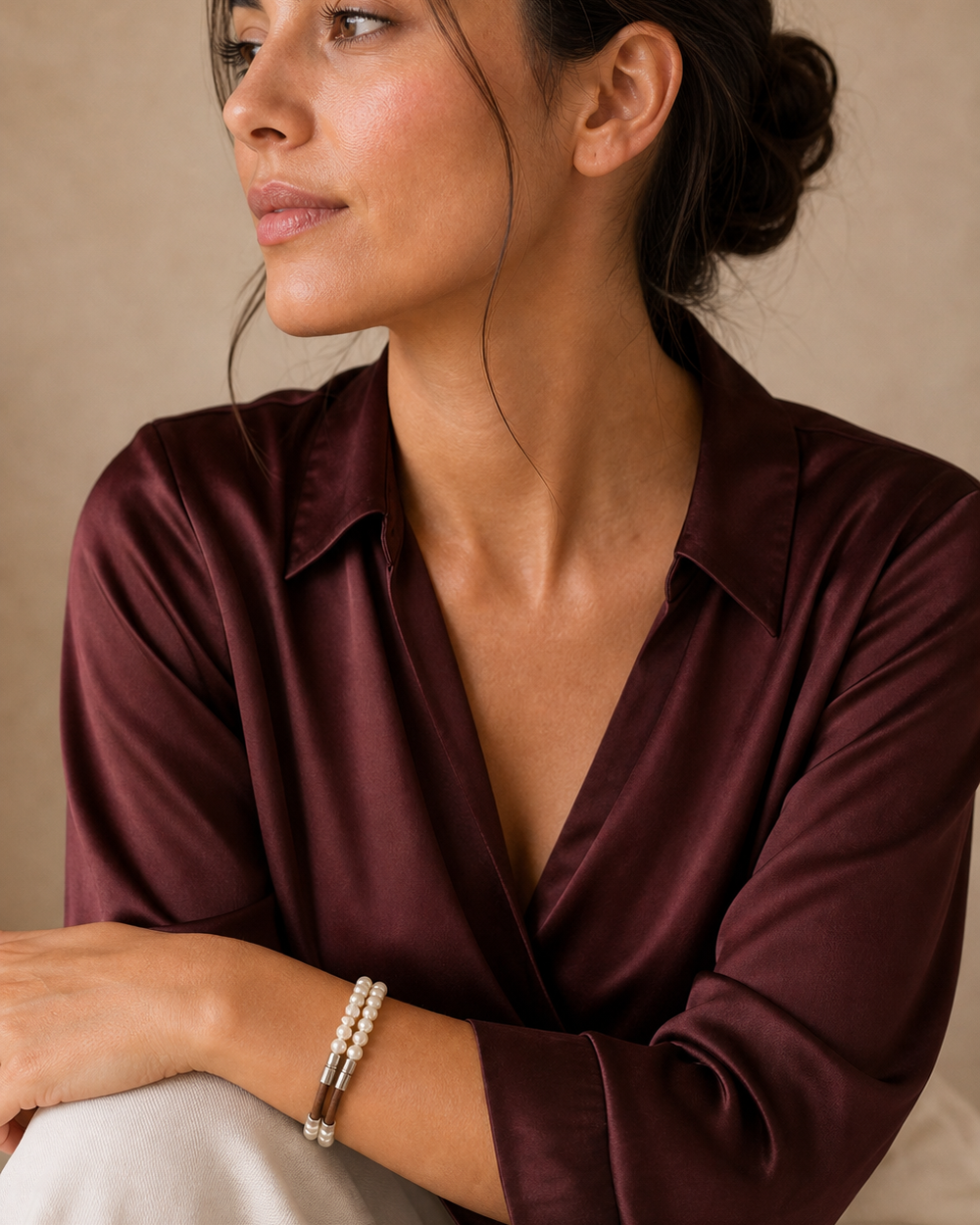 The Cognac Pearl Bracelet worn by a woman in a burgundy lifestyle portrait