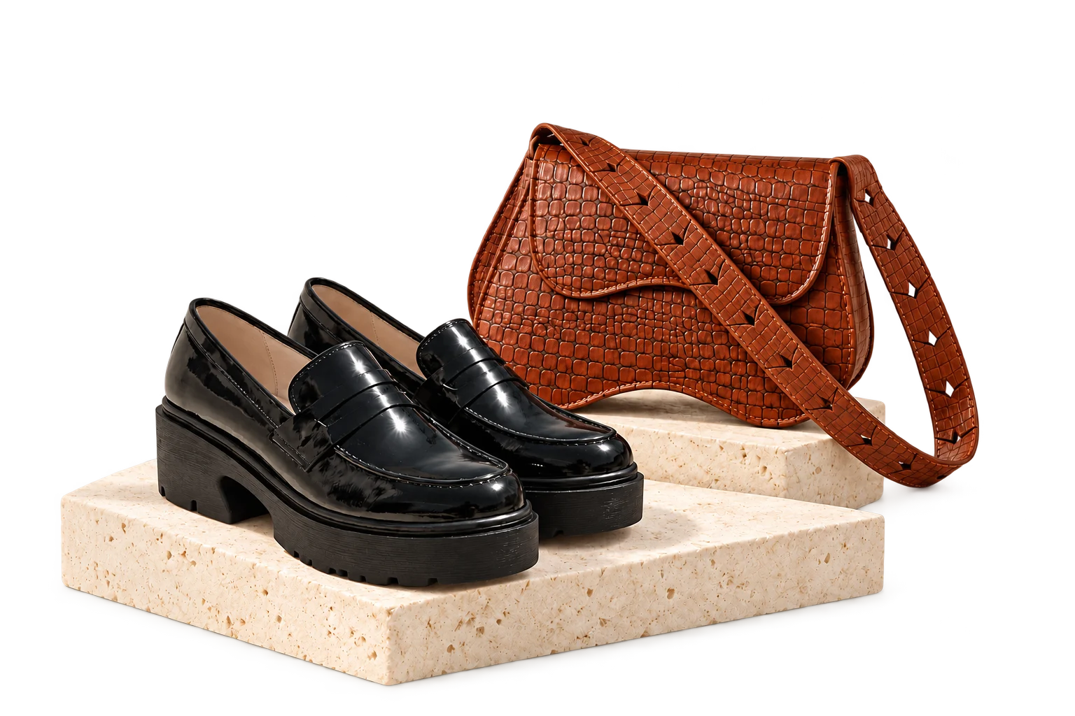 Black Blair loafers and the cognac Cindra croc bag arranged on pale stone plinths