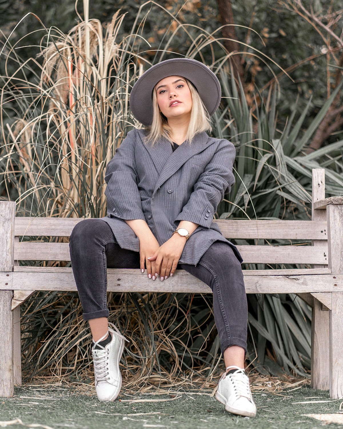 woman in gray coat sitting on brown wooden bench