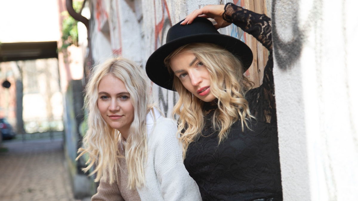 two women standing next to each other in front of a wall