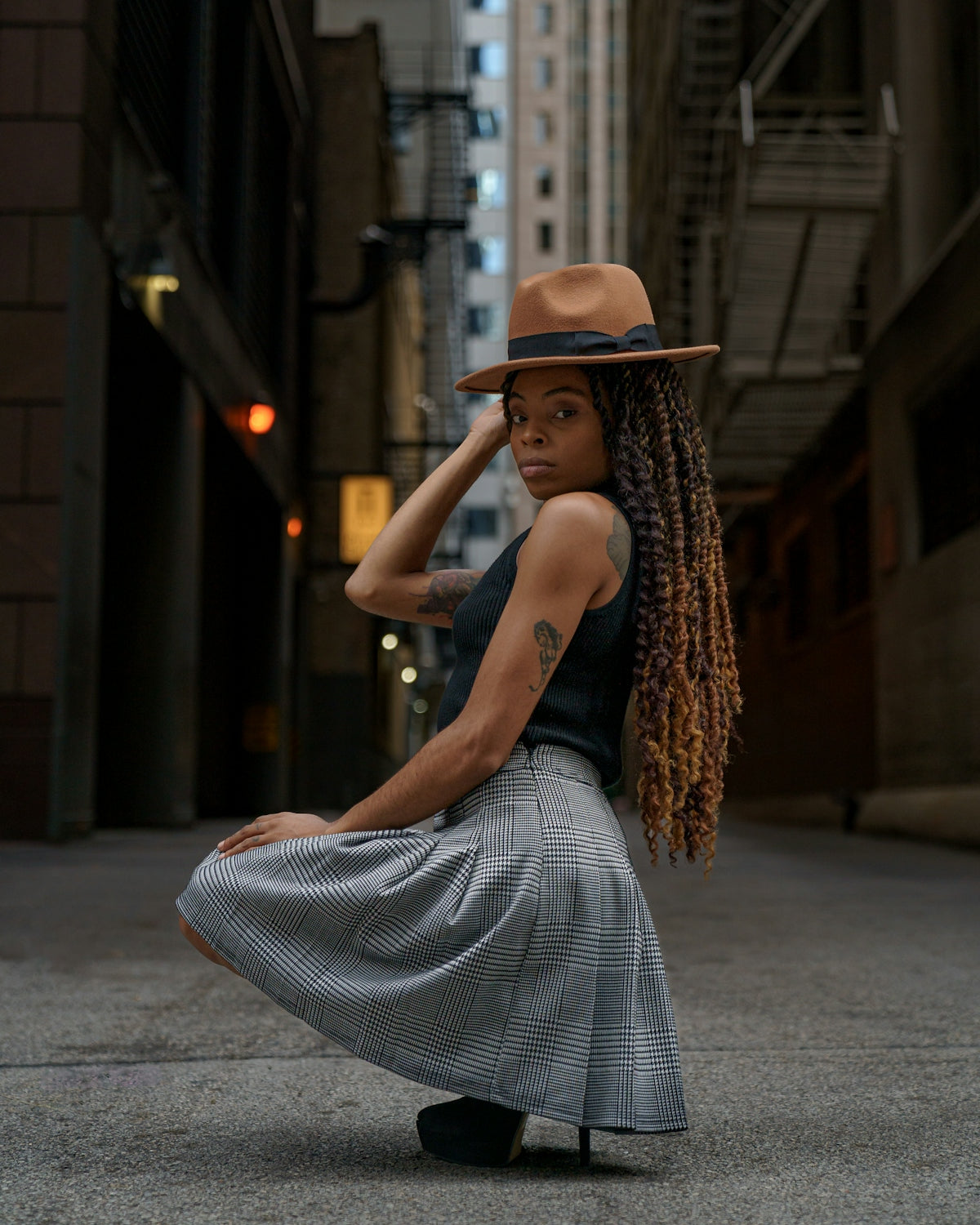 a woman in a hat and dress sitting on the ground
