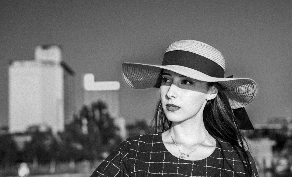 A woman poses wearing a wide-brimmed hat