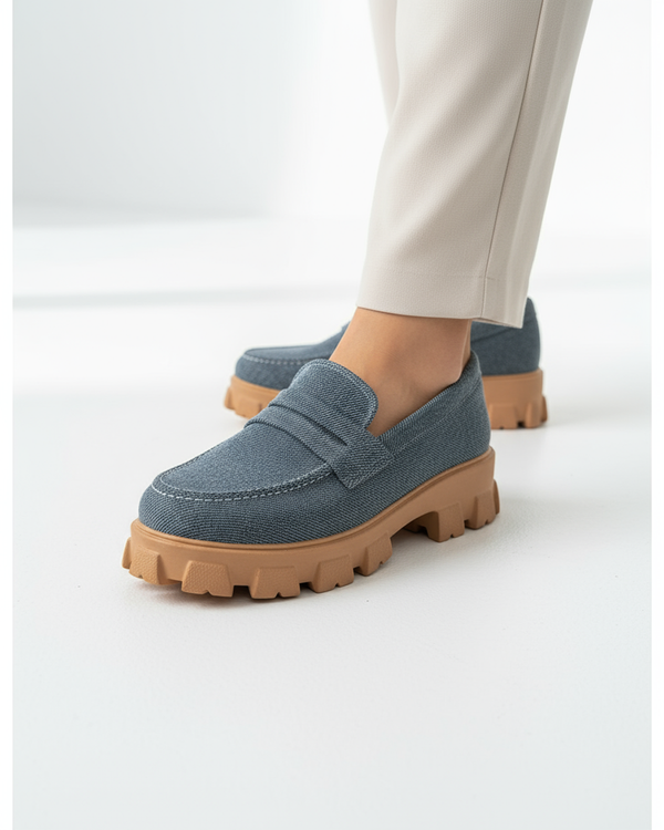Blue loafers with brown soles worn by a person on a white background