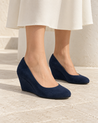Adult woman wearing Cadenza navy covered-wedge pumps, front three-quarter view