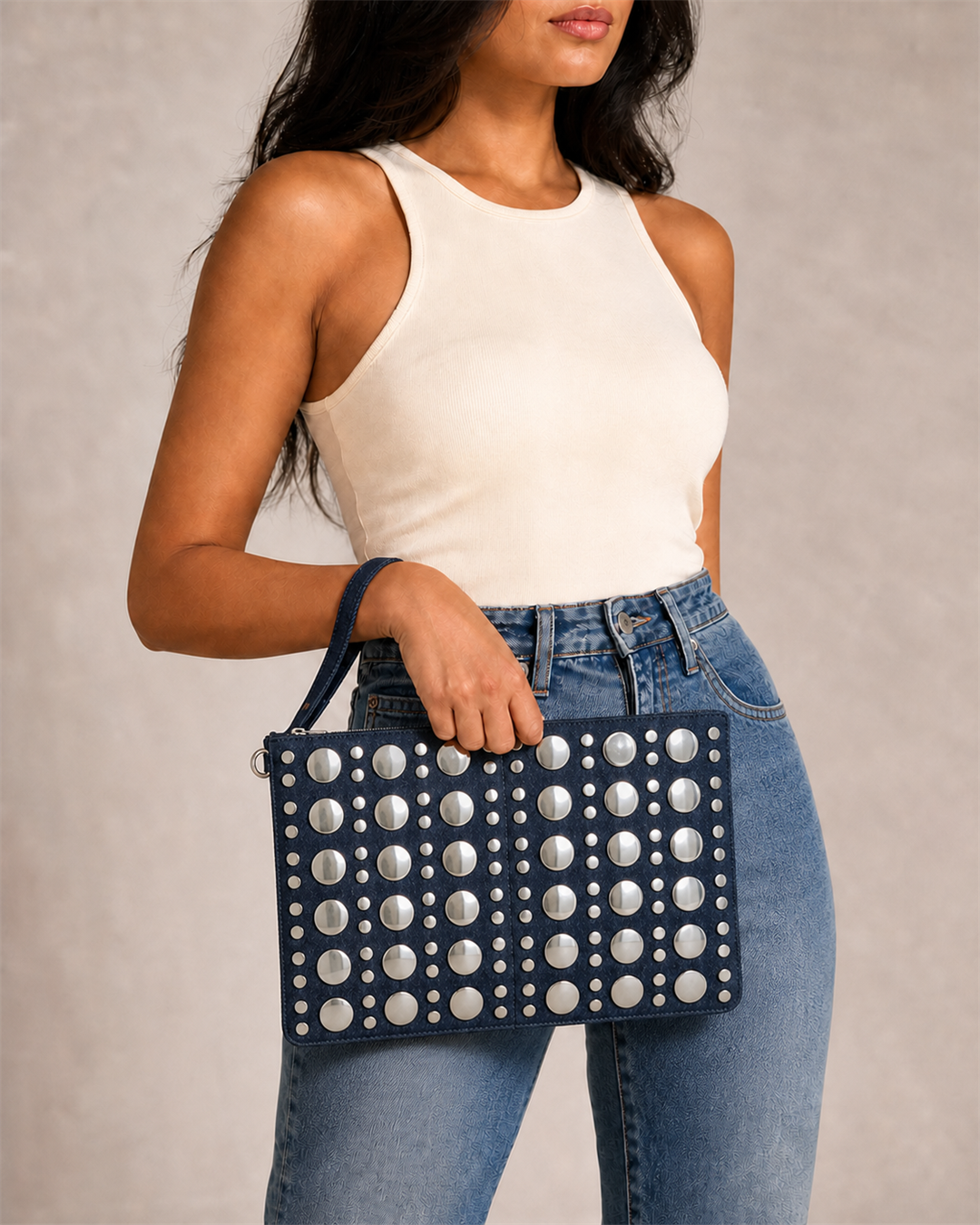 Denara dark-indigo studded denim clutch on female model in ivory top and jeans - view 1