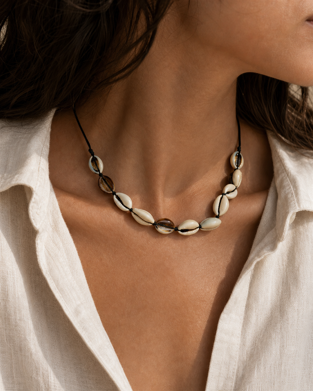 Marisca cowrie shell necklace on black cord on female model - view 1