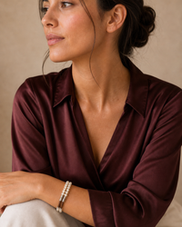 The Cognac Pearl Bracelet worn by a woman in a burgundy lifestyle portrait